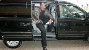 Mathew Knowles posing for a photo with his car